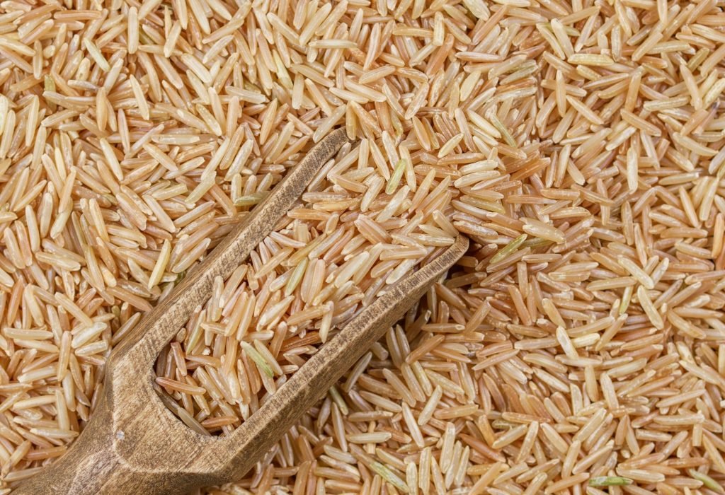 Detailed close-up of organic brown rice grains with a wooden scoop showcasing texture and natural colors.