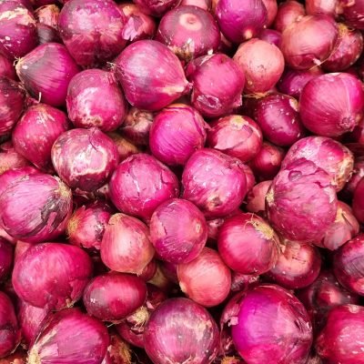 A vibrant photo showcasing a heap of fresh red onions at a market in Brasil.