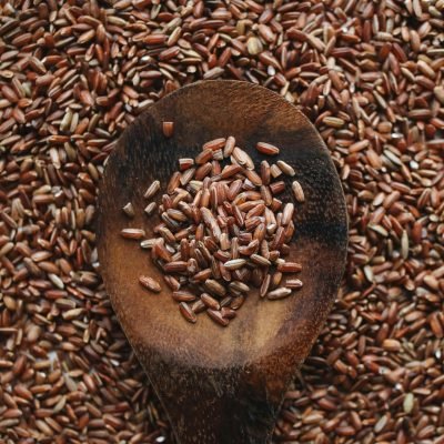Close-up of a wooden spoon filled with raw brown rice grains, ideal for food and nutrition concepts.