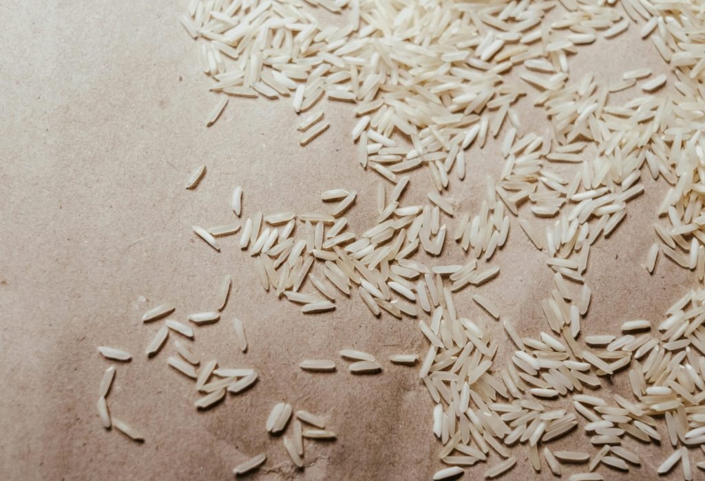 A detailed macro shot of uncooked basmati rice scattered on brown paper, showcasing its natural texture and organic grains.